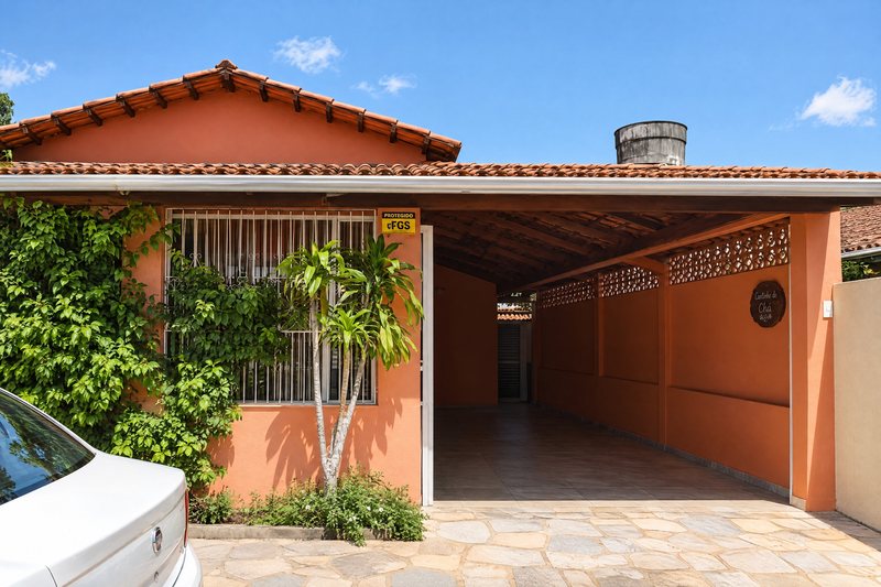 Fachada da casa, com portão de garagem e plantas na calçada